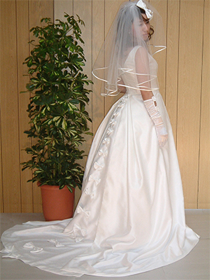 ウエストはほっそりとすそに向かって幸せのリボンが並ぶエレガントで豪華なバッスルスタイルのウェディングドレス